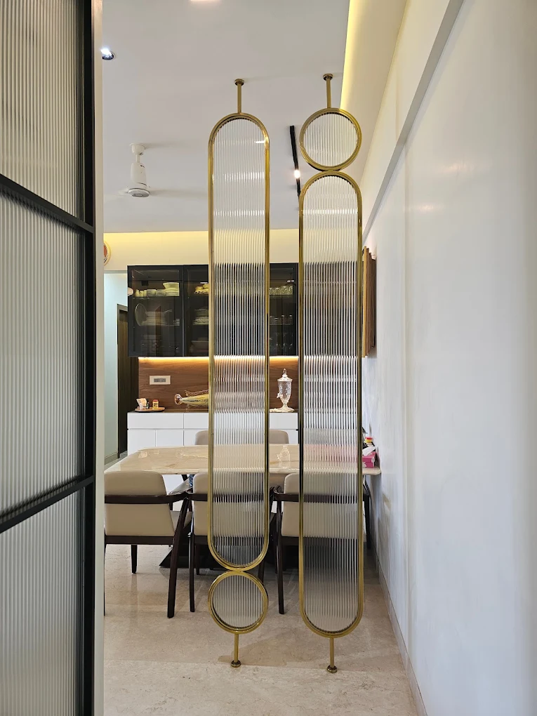 Brass-framed fluted glass partition leading to a dining area