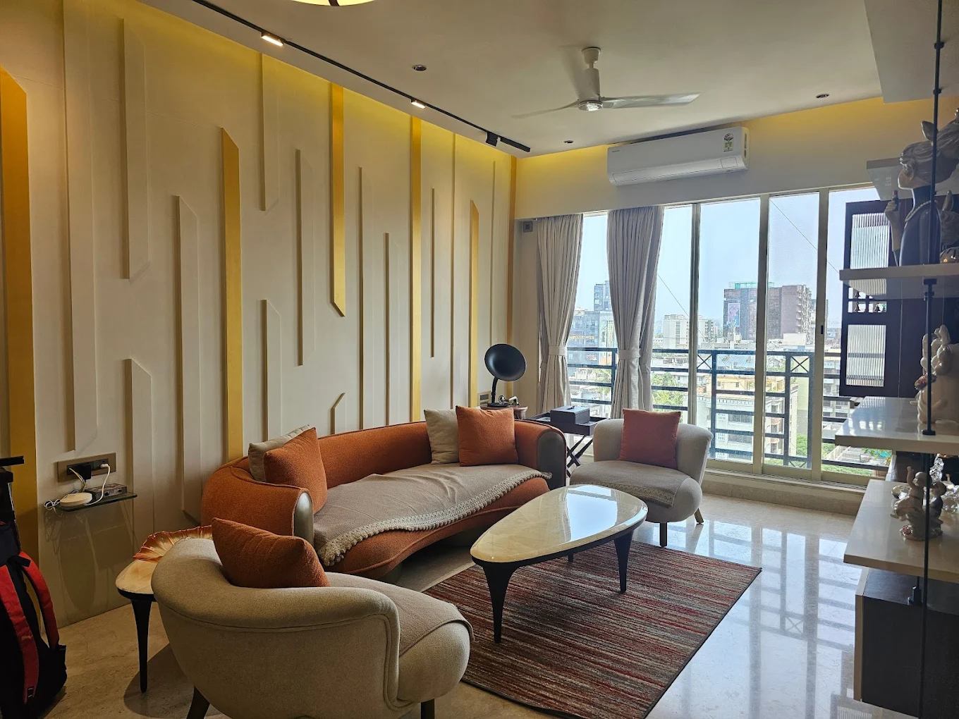 Living room with sculpted wall panelling, gold fins and track lighting