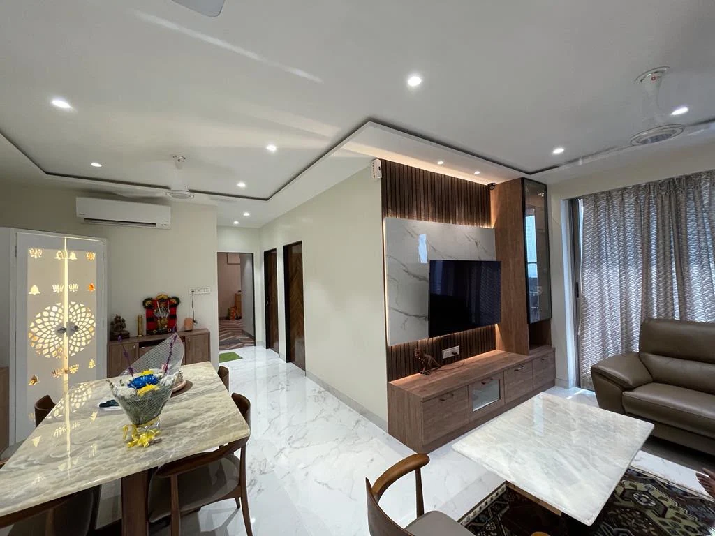Living and dining with marble-clad TV unit, fluted wood panels and cove ceiling